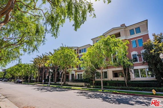 Front view of a multi-story building with trees lining the sidewalk.