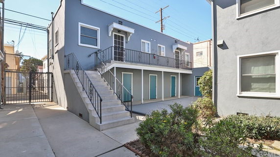 Front view of a two-story building with an external staircase and multiple doors.