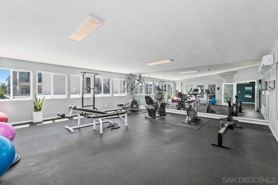 Room equipped with gym equipment including stationary bikes and weight bench.