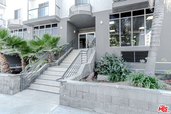 Front view of a multi-story building with large windows and entrance stairs.