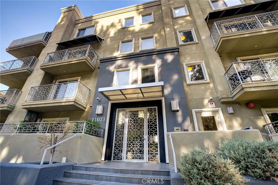 Front view of a multi-story apartment building with decorative balconies and a modern entrance.