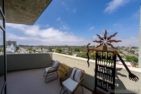 Balcony view overlooking a cityscape with chairs and decorative artwork.