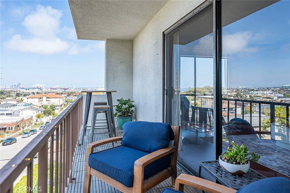 Balcony view with outdoor seating and wide-angle scenery of surrounding area.