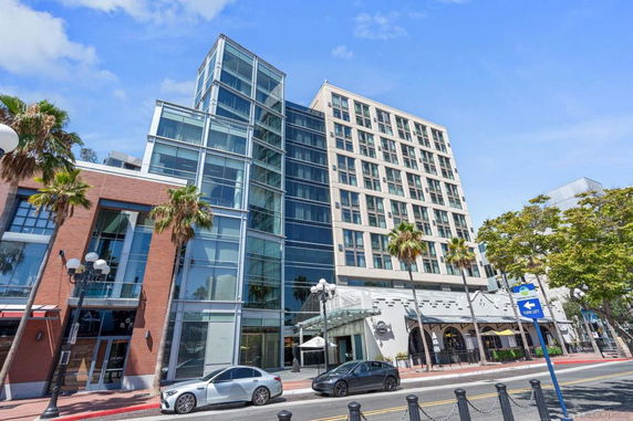 Front view of a modern multi-story building with a glass facade and adjacent brick structure.
