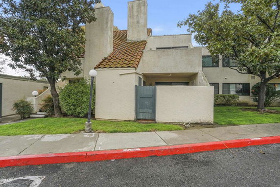 Front view of a multi-story building with a tiled roof and stucco exterior.