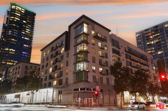 Front view of a multi-story residential building at dusk, with large windows and balconies.