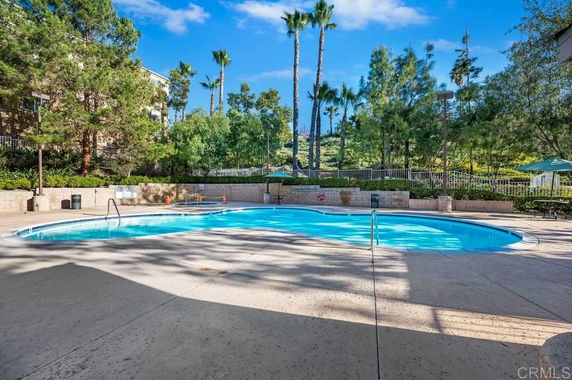 Outdoor swimming pool surrounded by trees and fencing.