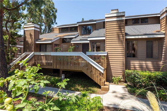 Front view of a multi-story house with wooden exterior and a central staircase.