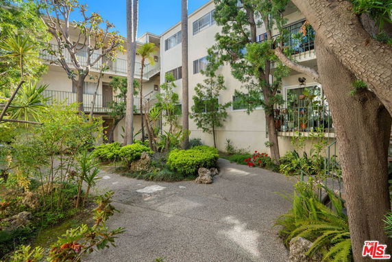 Front view of a multi-story residential building with surrounded by greenery.