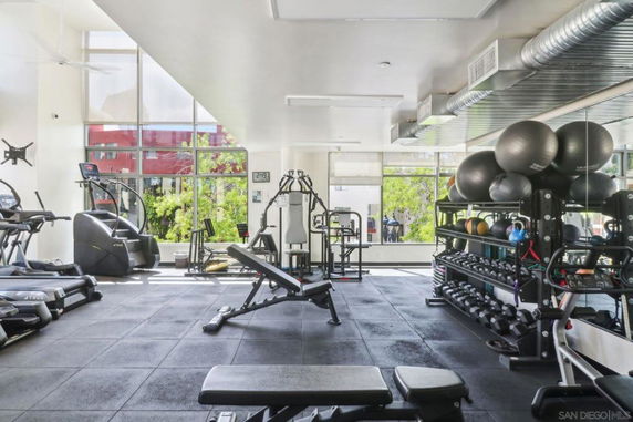 Interior view of a modern gym with exercise equipment and weights.
