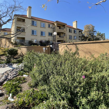 Front view of a multi-story residential building with balconies and a tiled roof.