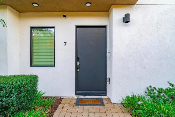 Front view of a house entrance with a black door and a window to the left.