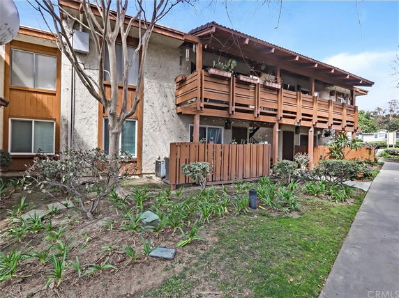 Front view of a two-story apartment building with balconies and wooden fencing.