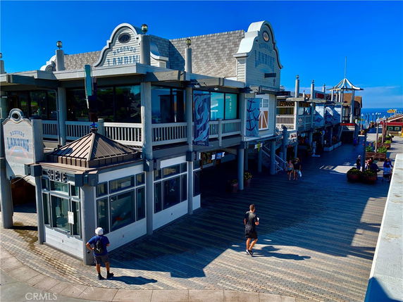 Front view of a two-story building with signage, featuring a boardwalk and activity area.