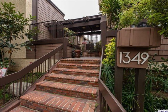Front view of a residential building with brick stairs and a wooden gate.