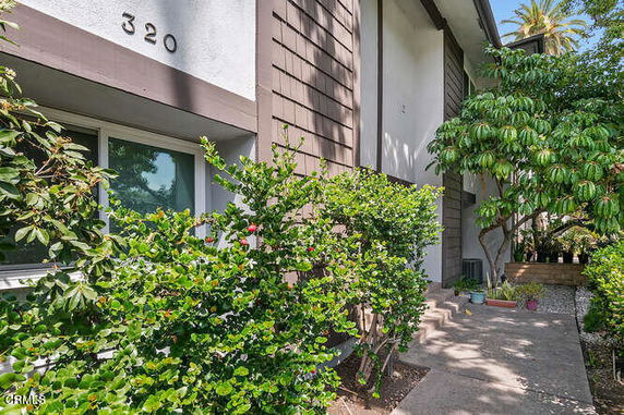 Front view of a house with bushes along the pathway.