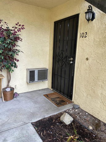 Entrance of a building with a metal door, light fixture, and a doormat.