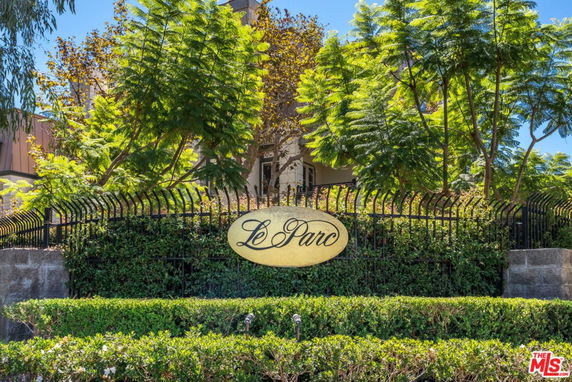 Front view of a building with a sign reading 'Le Parc' and surrounded by greenery.