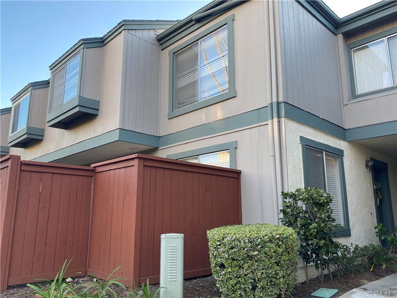 Front view of a two-story townhouse with a fenced patio.