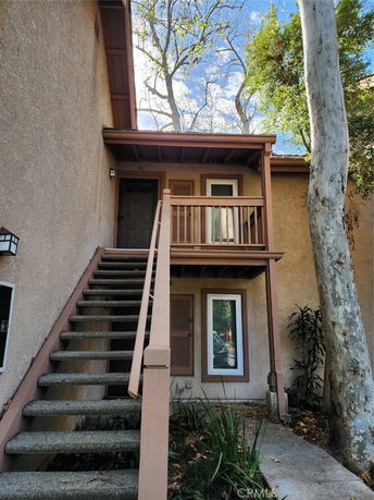 Front view of a two-story house with an exterior staircase leading to an upper entrance.