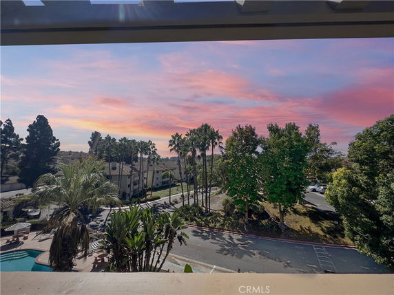Panoramic view of residential complex with trees and a swimming pool at sunset.