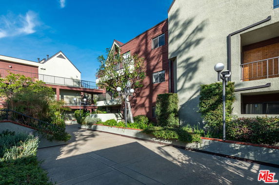 Front view of a multi-story residential building with a pathway and landscaping.