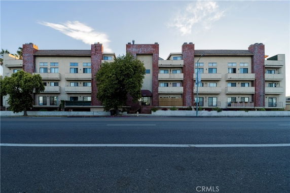 Front view of a multi-story apartment building with a brick facade and balconies.