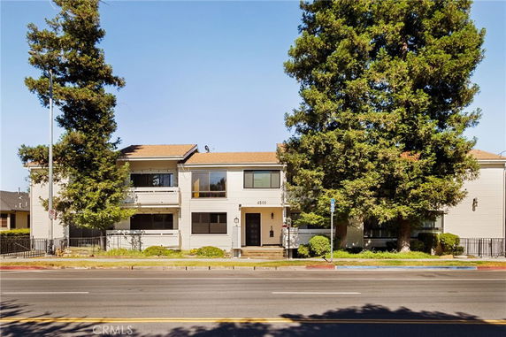 Front view of a two-story building with trees on either side and a main entrance in the center.