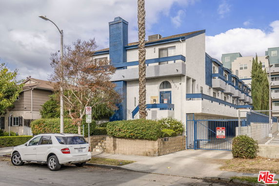 Front view of a multi-story building with blue accents and gated entrance.