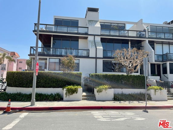 Front view of a modern multi-story building with large glass windows and balconies.