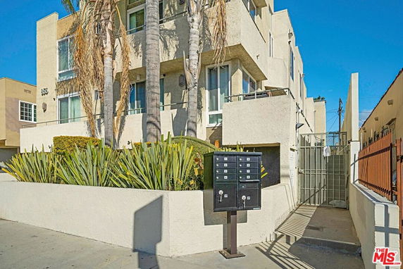Front view of a multi-story apartment building with large windows and a gated entrance.