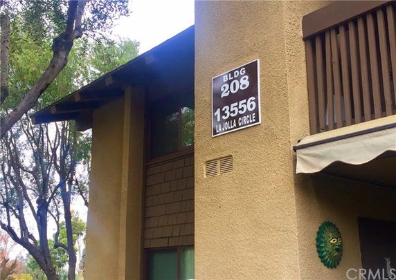 Front view of a multi-story building with a visible balcony and address sign.
