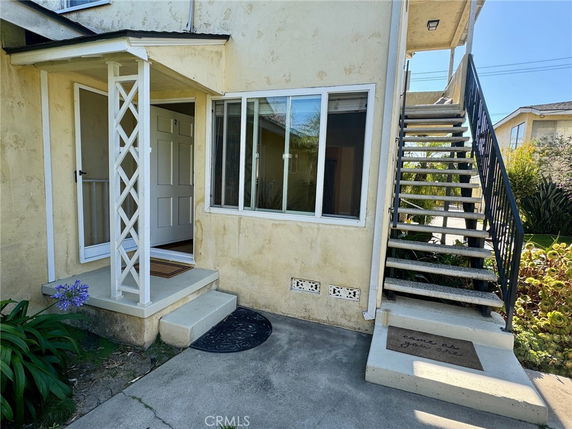 Front view of a house with an external staircase and a small porch.