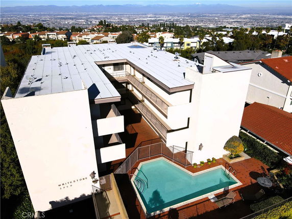 Panoramic view of a multi-story building with a swimming pool and surrounding residential area.