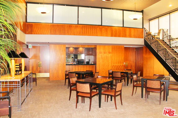 Interior view of a clubhouse with tables and chairs, wooden walls, and a staircase.
