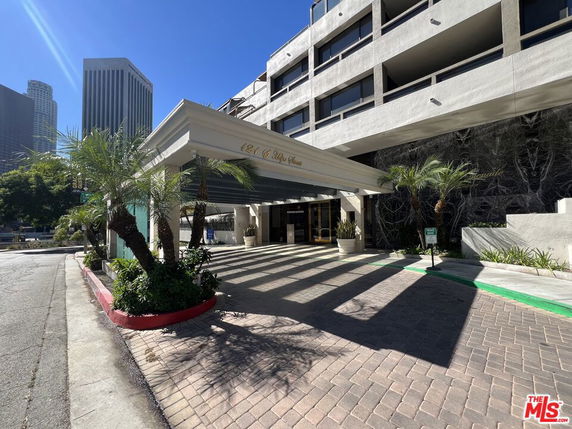 Front view of a building with a covered entrance and surrounding palm trees.