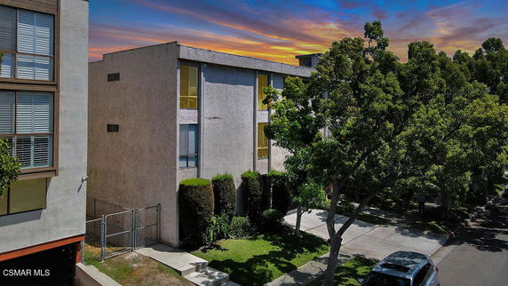 Front view of a multi-story building with large windows and surrounding trees.