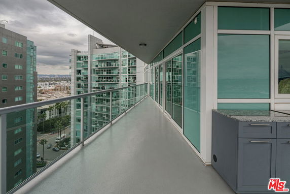 Balcony view of a high-rise building with glass railings and cityscape in the background.