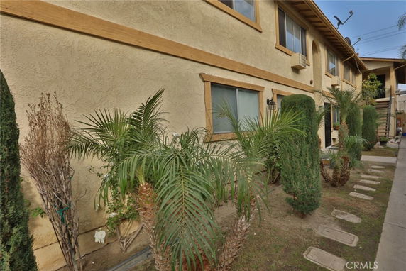 Front view of a two-story building with beige stucco walls and wooden trim.
