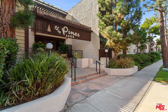 Front view of a multi-story building named 'The Pines' with a modern entrance and landscaping.