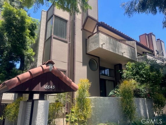 Front view of a multi-story building with balconies and a sloped roof.