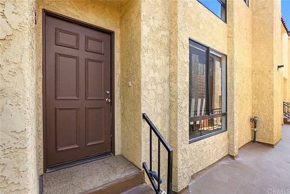 Front view of a building entrance with a brown door and yellow textured walls.