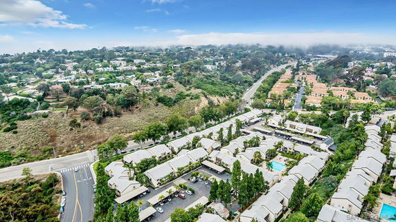Aerial view of a residential area with multiple buildings, roads, and green surroundings.