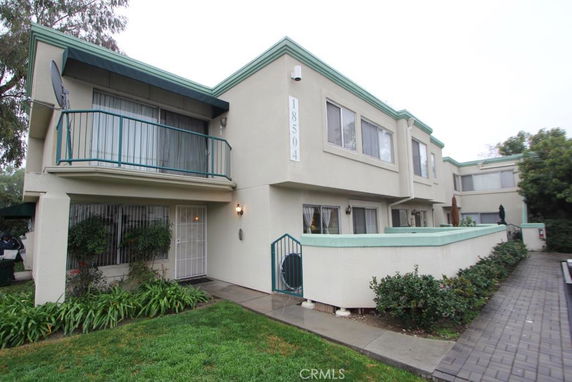 Front view of a two-story residential building with balconies and a numbered wall decor on the side.