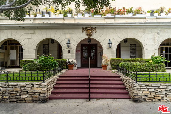 Front view of a building with arched entrances and decorative plants.