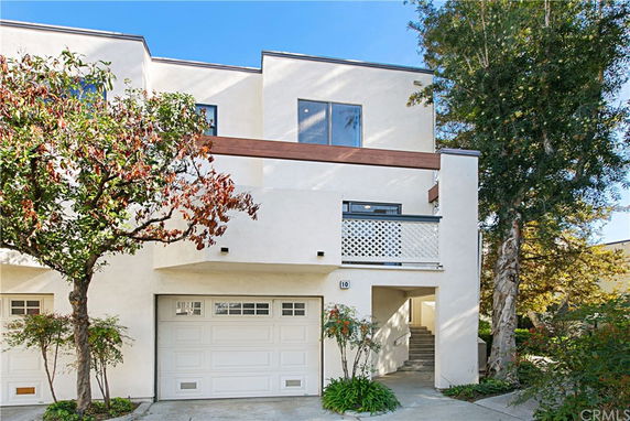 Front view of a modern, multi-story house with a garage and balcony.
