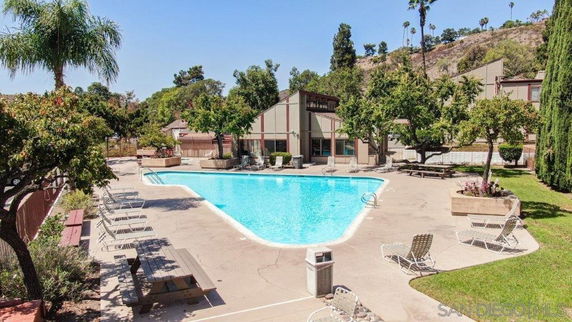 Swimming pool area with surrounding trees and lounge chairs.