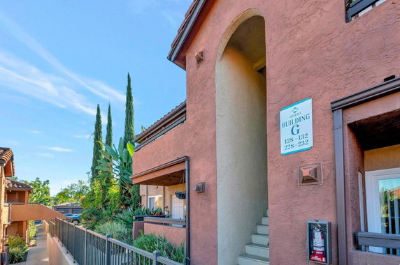 Front view of an apartment building with stucco walls and outdoor stairs.