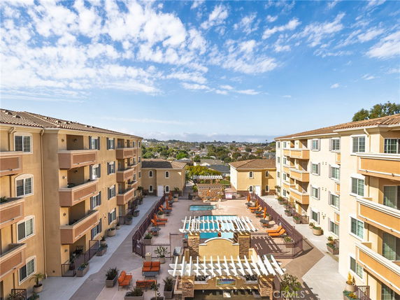 Panoramic view of apartment buildings surrounding a swimming pool with outdoor seating.