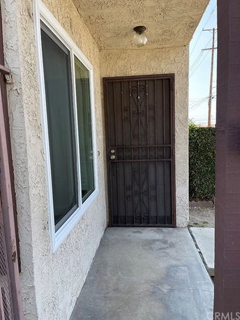 Front entrance of a house with an iron security door and adjacent window.